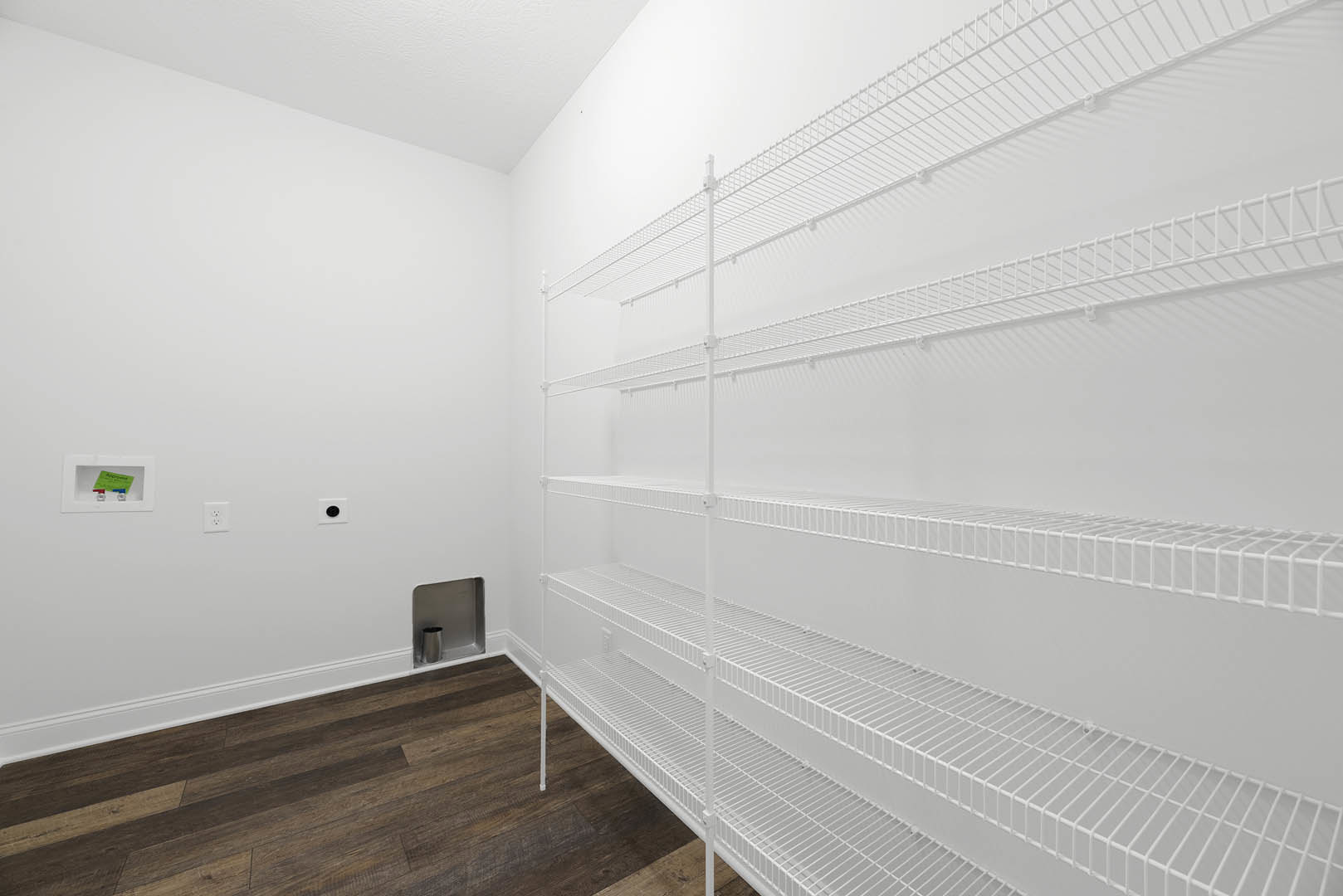 White built-in shelves against a white wall, wood floor with white baseboard, green card with red and blue pipes, silver cup in recessed shelf.
