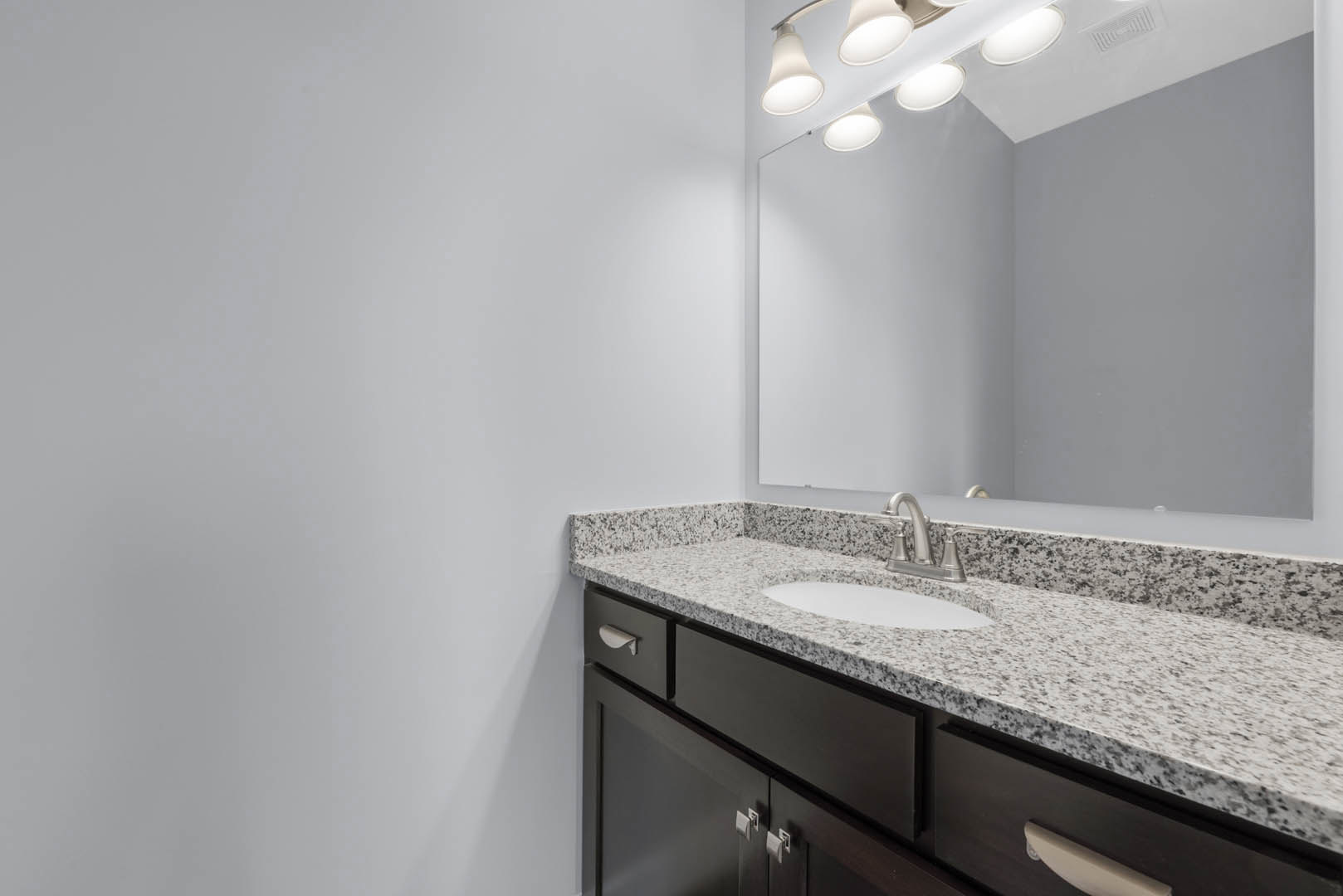 Modern bathroom with white tile walls, rectangular mirror above a sleek sink, chrome faucet, and built-in cabinetry with drawers
