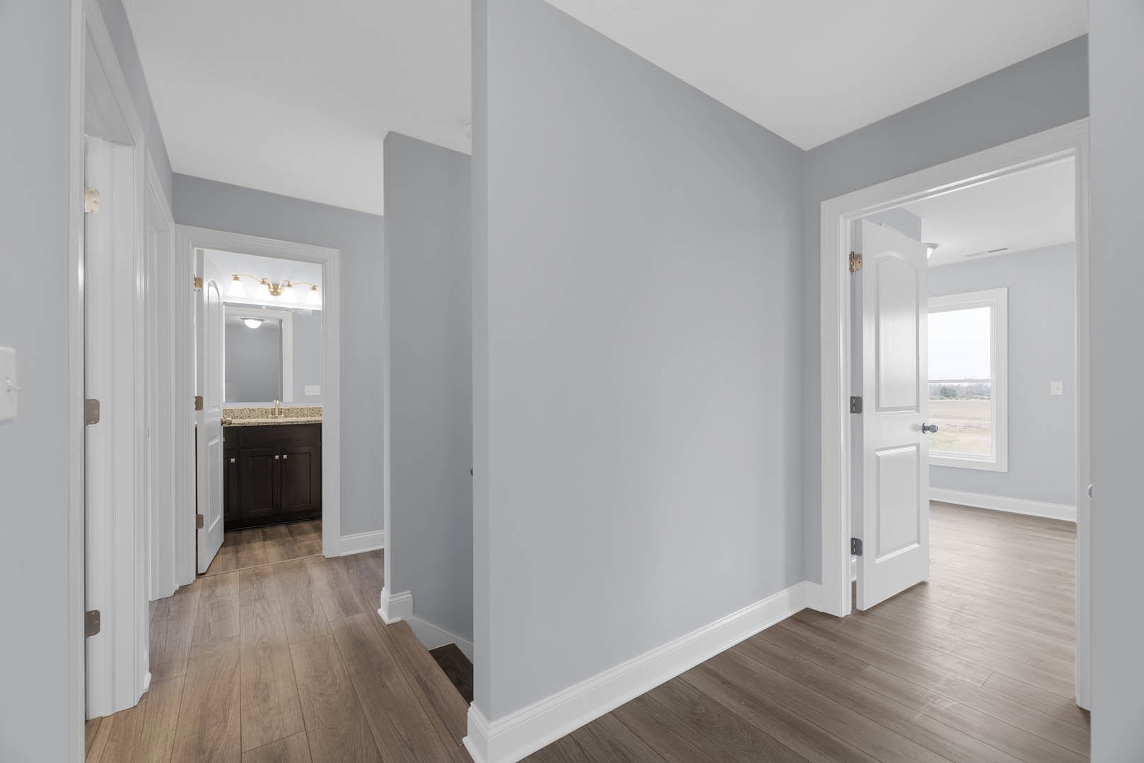 Hallway with smooth white plaster walls, natural hardwood flooring, and a white door featuring a window panel