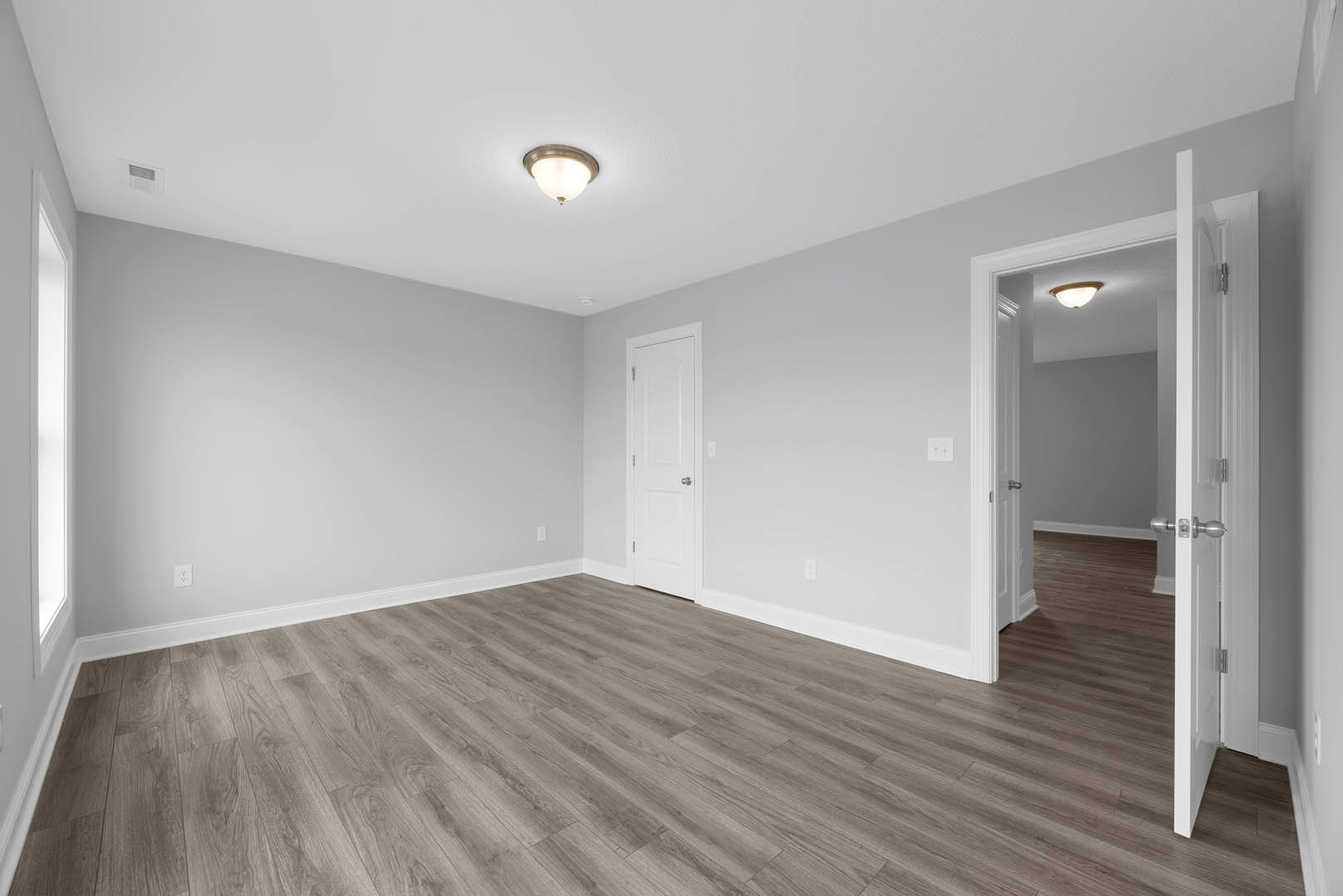 Wood flooring, white walls, white door with silver knob, rectangular window, ceiling light fixture