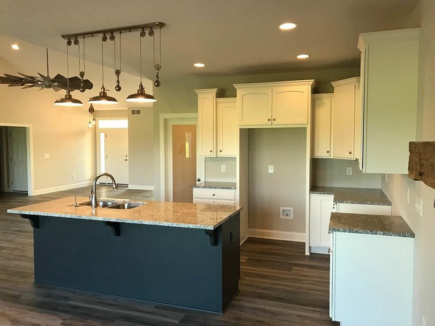 Marble kitchen island with built-in sink, white cabinetry, ceiling light fixture, wall-mounted light switch, and square outlet with silver knob