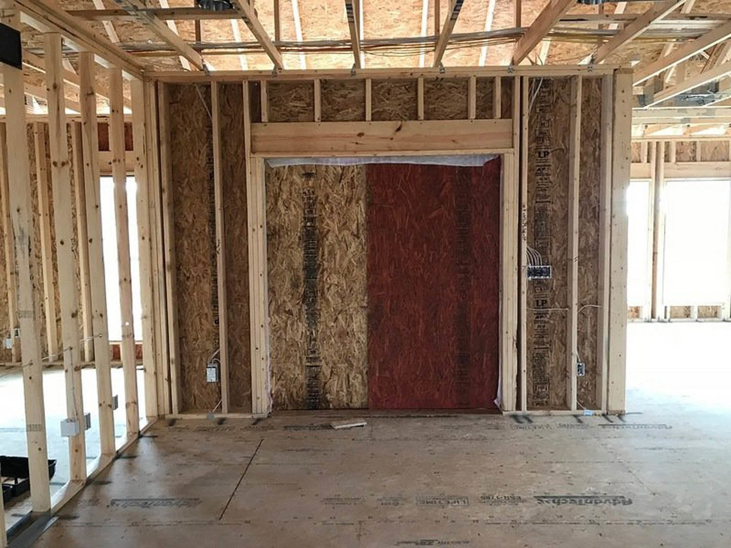 Modern interior room featuring a red and white door, large window, exposed wood beam, polished concrete floor, and a dog bed near the wall.