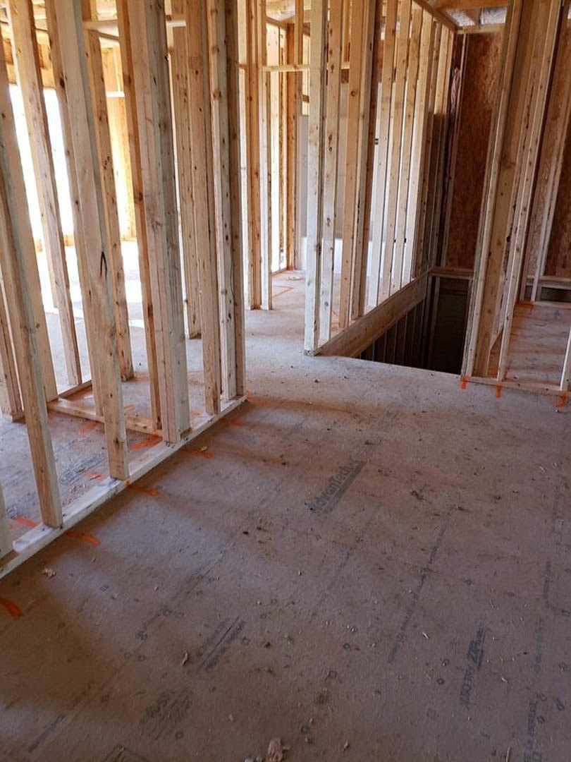 Room under construction with exposed wood framing, beams, and unfinished walls