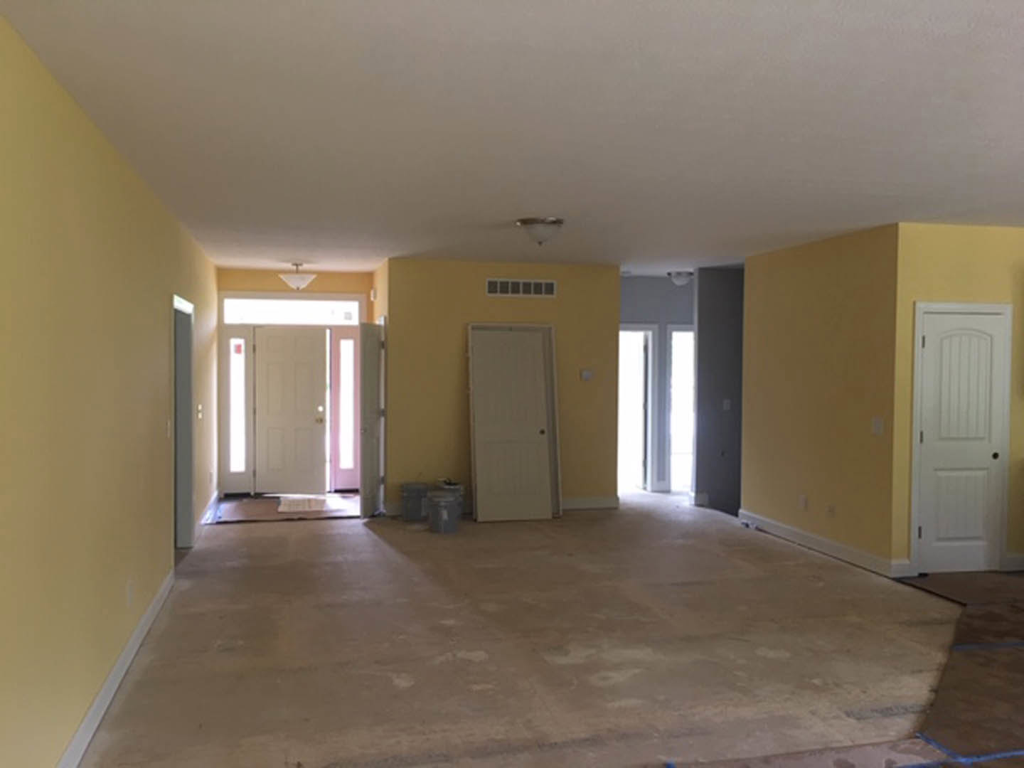 Yellow-painted walls, white door with black knob and yellow trim, light fixture on white ceiling, neutral flooring