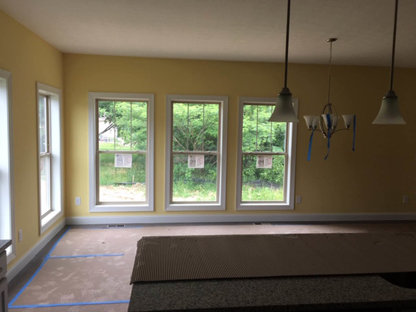 Spacious room featuring multiple windows with white trim, neutral walls, hardwood flooring, and a modern ceiling light fixture