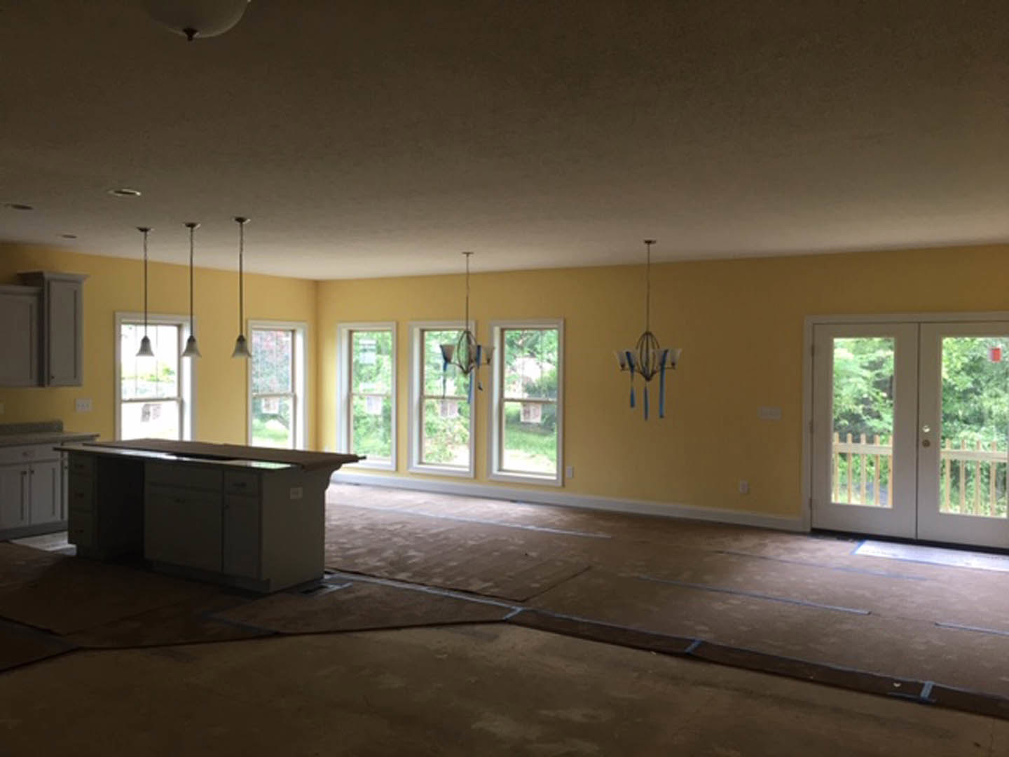 Bar area with white countertop, glass double doors, large windows showing exterior sign, light fixture detail, and smooth plaster walls over hardwood flooring
