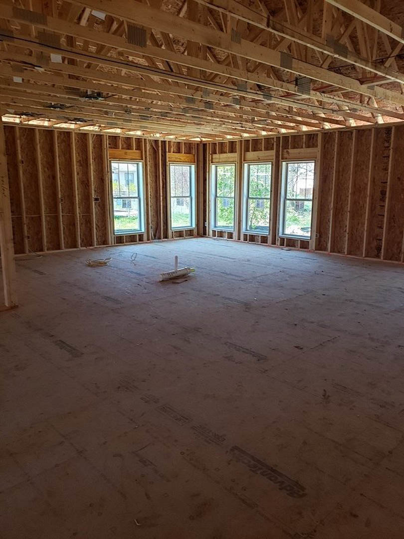 Living room with exposed wood ceiling beams, large windows, light-colored walls, and hardwood flooring