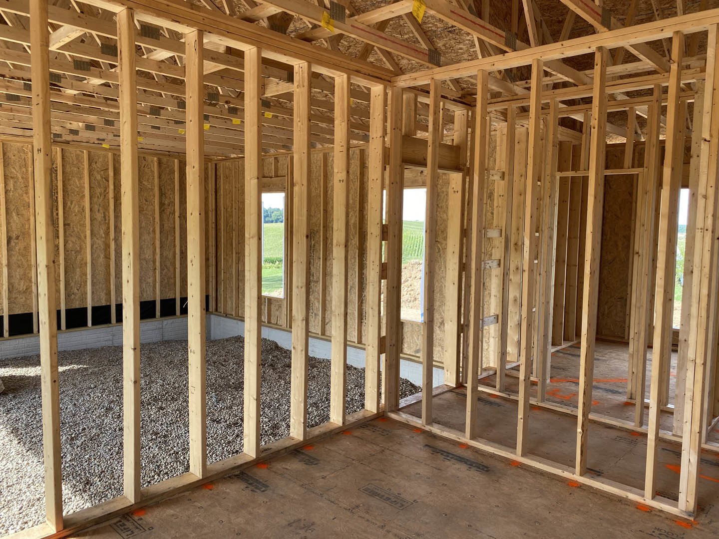 Open room featuring a prominent wood accent wall, exposed ceiling beams, hardwood flooring, and a large window framed in natural lumber.