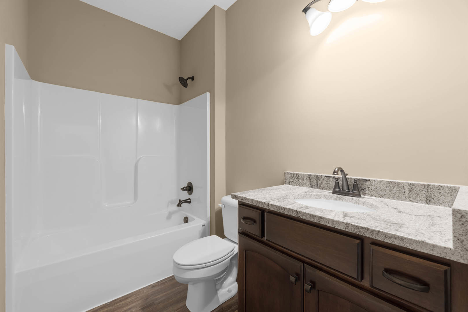 Modern bathroom featuring a white bathtub, wall-mounted black shower head, white toilet with seat down, and a close-up of a rectangular sink set in a tiled vanity.