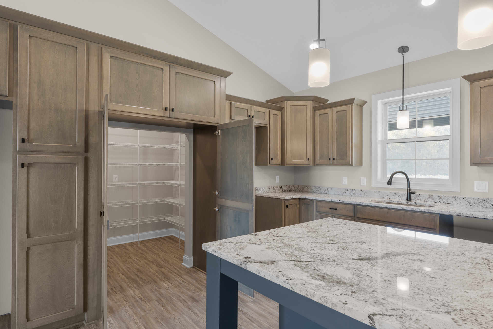 Marble kitchen island with blue base, white tile backsplash, stainless steel sink, and modern pendant light fixtures