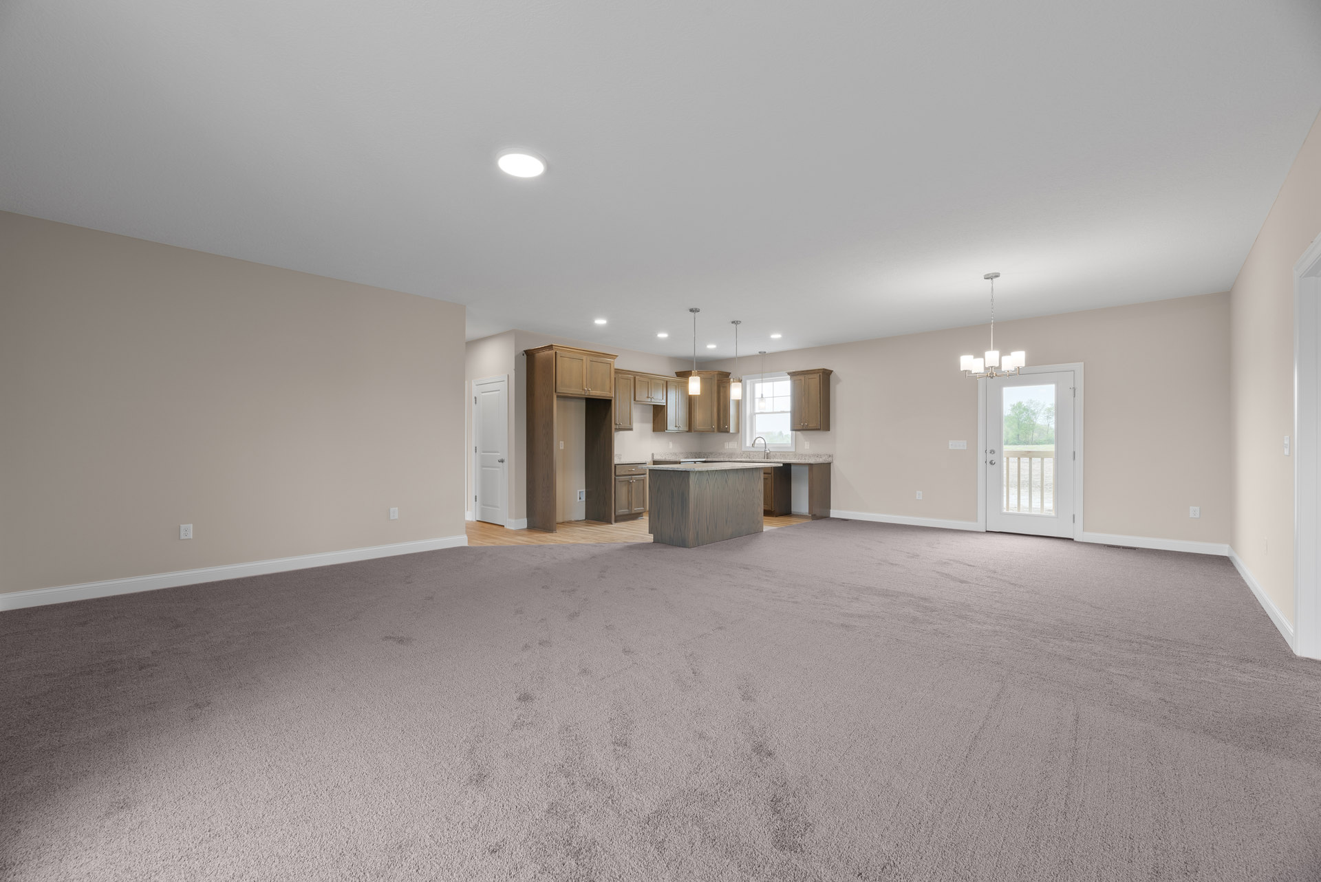 Open kitchen and dining area with marble-topped island, laminate flooring, plaster walls, molding accents, and a door overlooking foggy trees and grassy yard