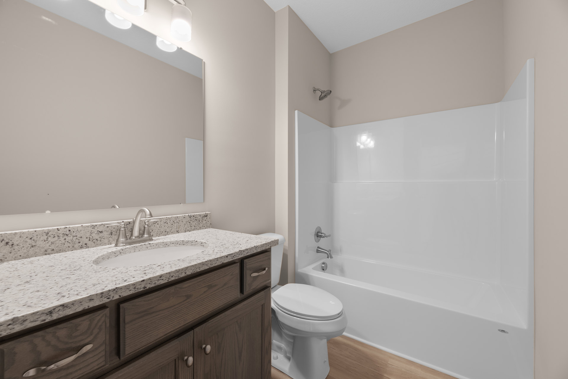 Modern bathroom with white tile walls, built-in vanity with sink and chrome faucet, white toilet, and partial view of a white bathtub
