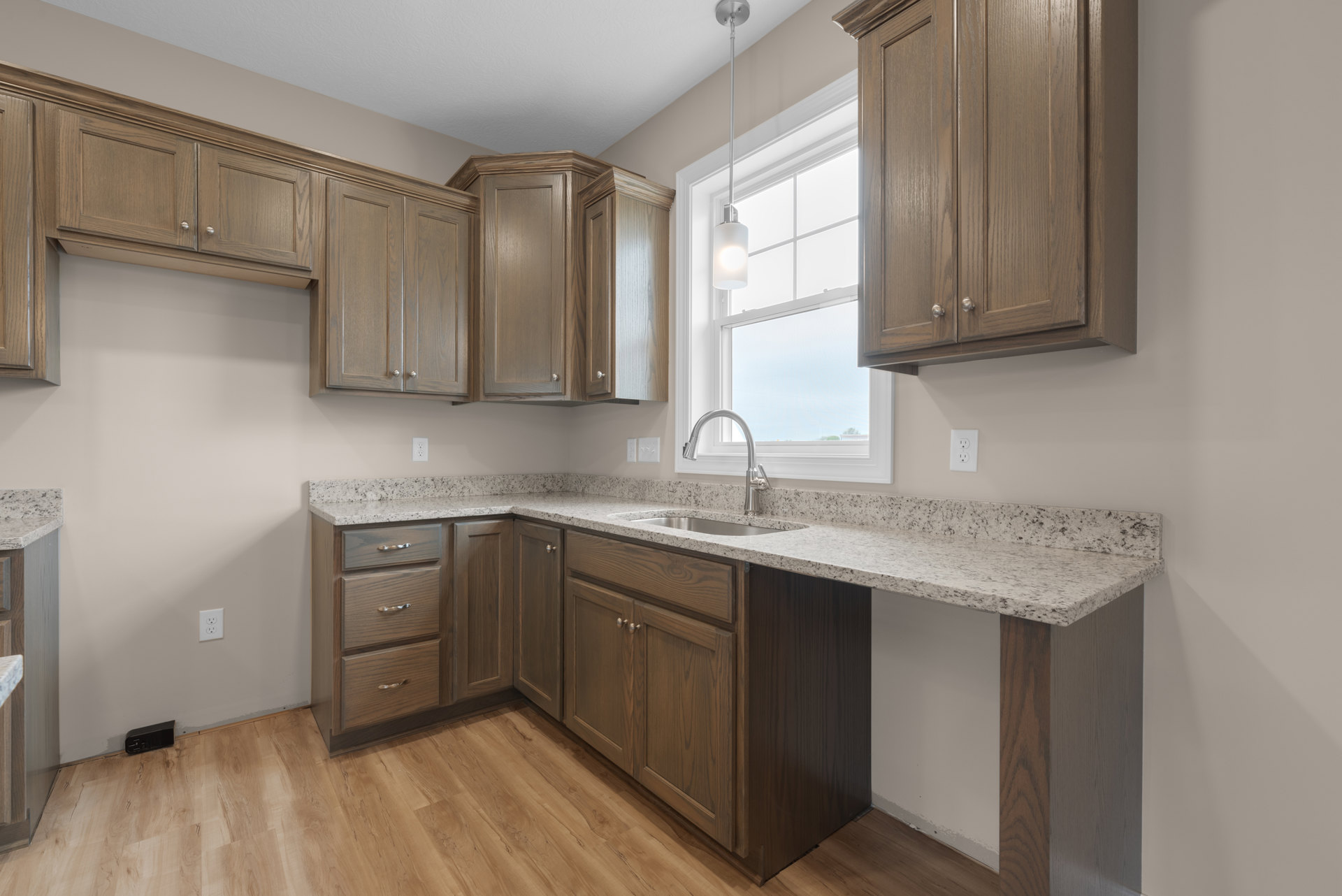 Modern kitchen featuring wooden cabinets, stainless steel sink with chrome faucet, stone countertop, built-in drawers, and recessed ceiling light.