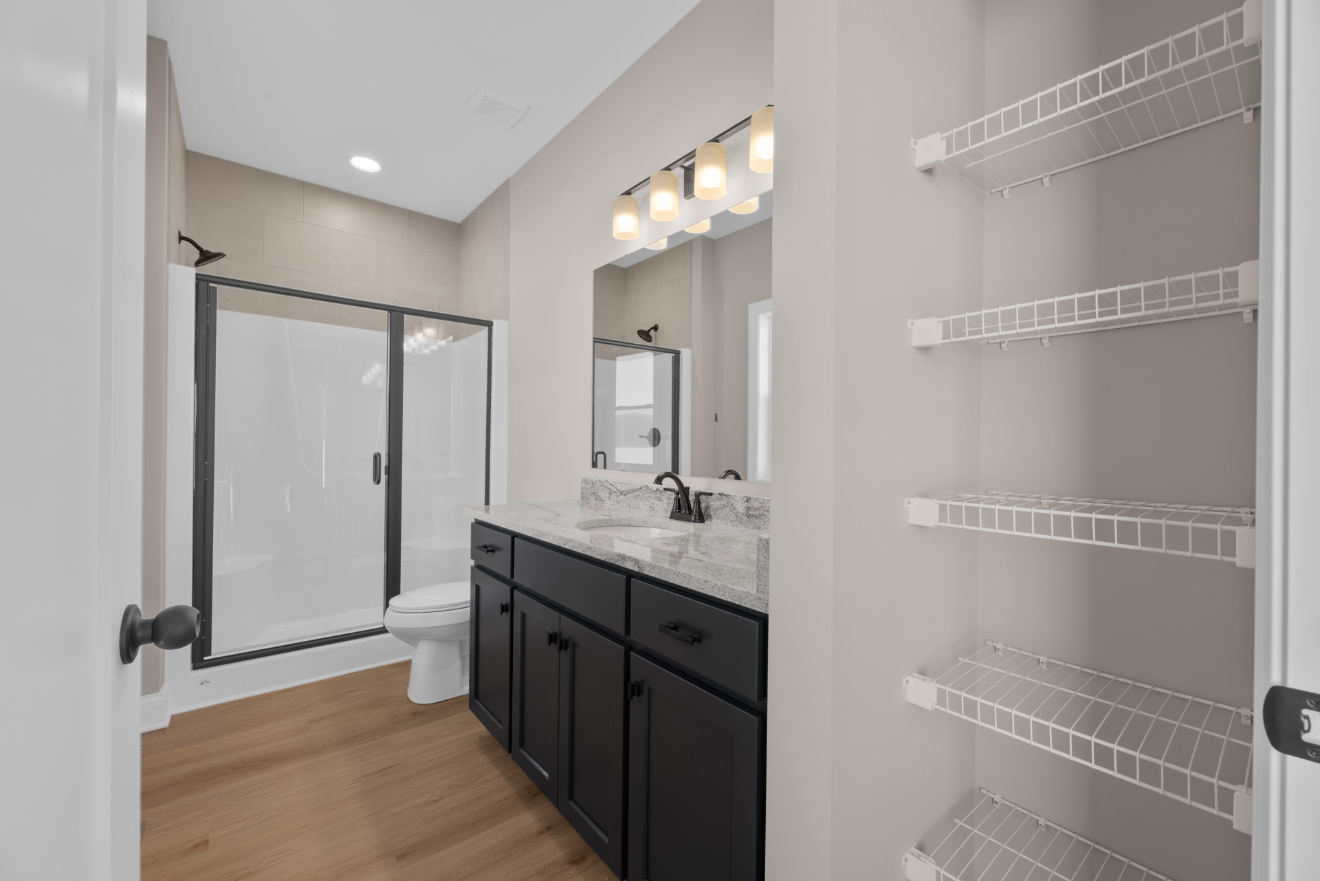 Modern bathroom featuring a glass-enclosed shower, white ceramic sink with chrome faucet, light tile walls, and minimalist cabinetry