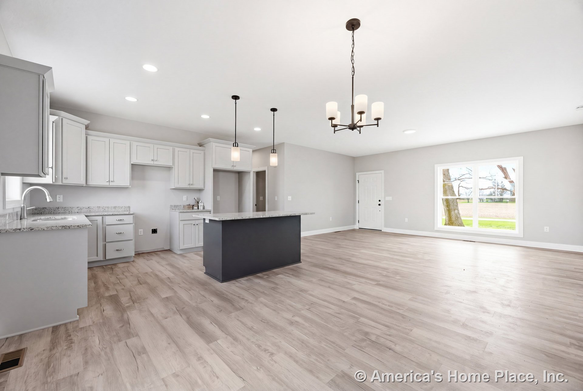 Open concept kitchen and living area with light wood plank flooring, white shaker cabinets, granite countertops, large island, pendant and chandelier lighting, recessed lights, and