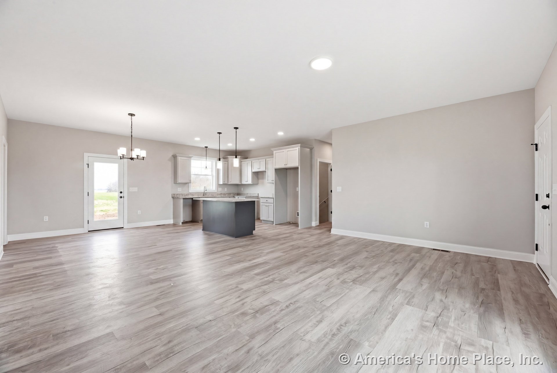 Open-concept kitchen and living area with white shaker cabinets, kitchen island, pendant and recessed lighting, light wood-look vinyl plank flooring, glass-panel exterior door