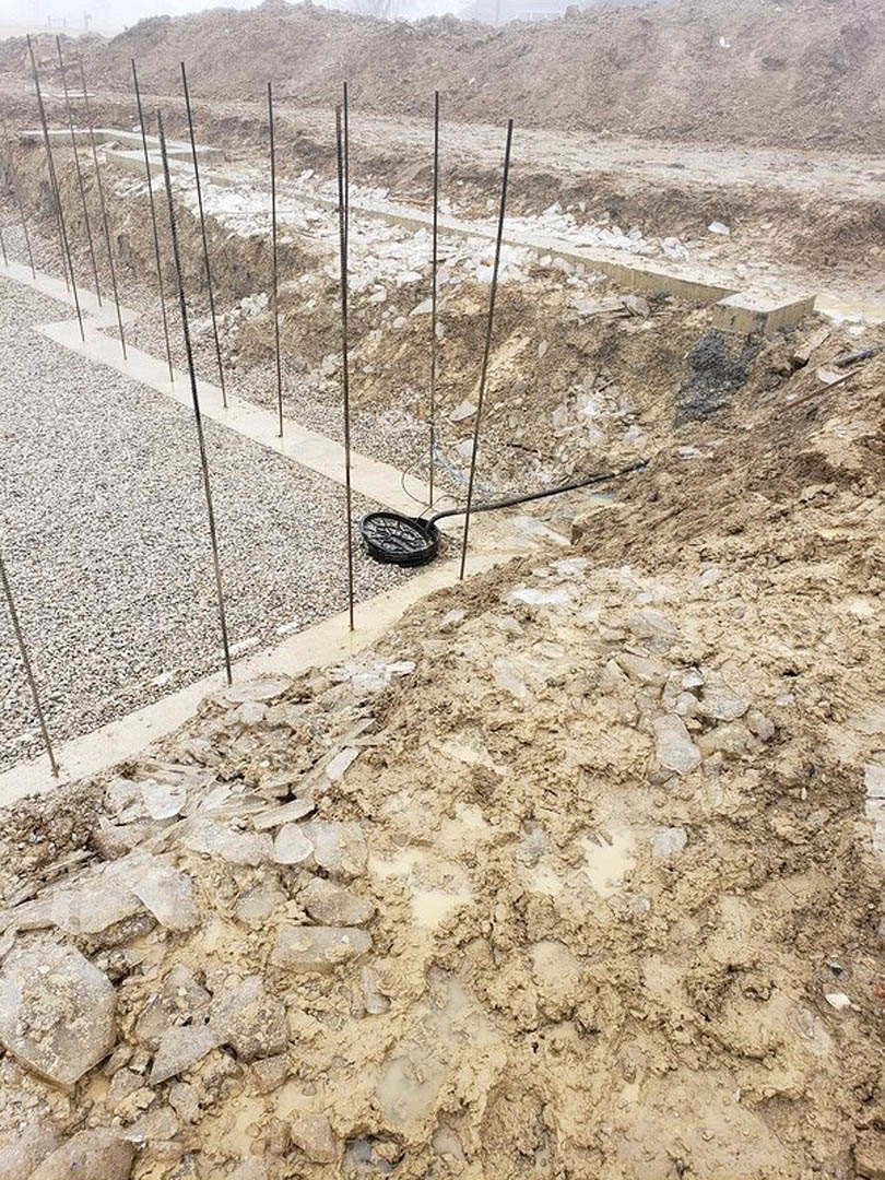 Wire fence enclosing a patch of dry soil and rocks in a desert landscape under an open sky