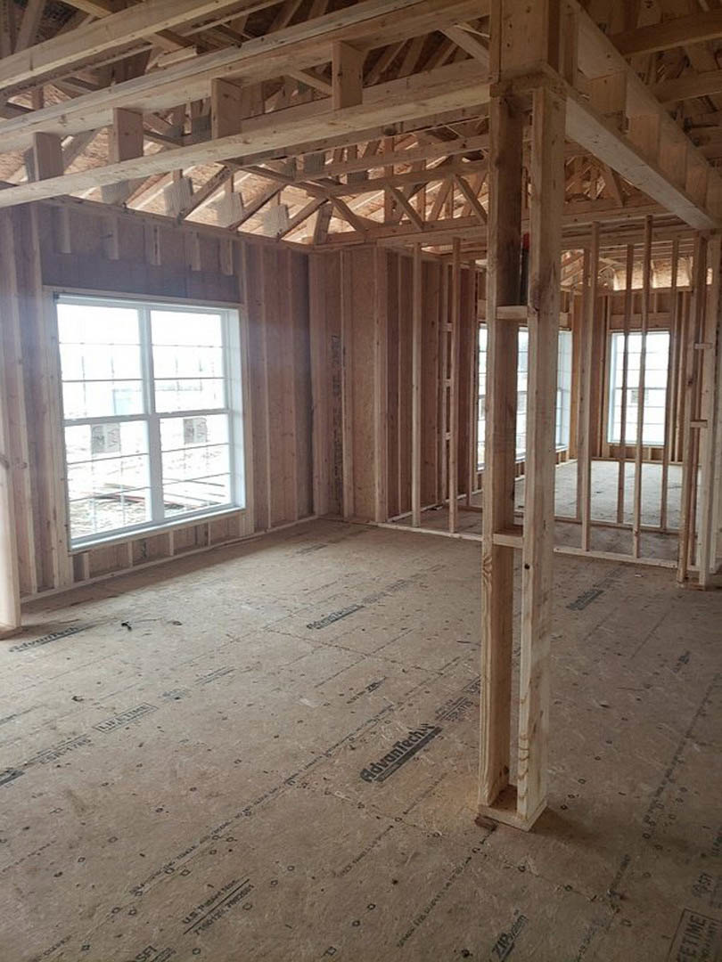 Room with exposed wood ceiling beams, large window with white frame, and hardwood flooring
