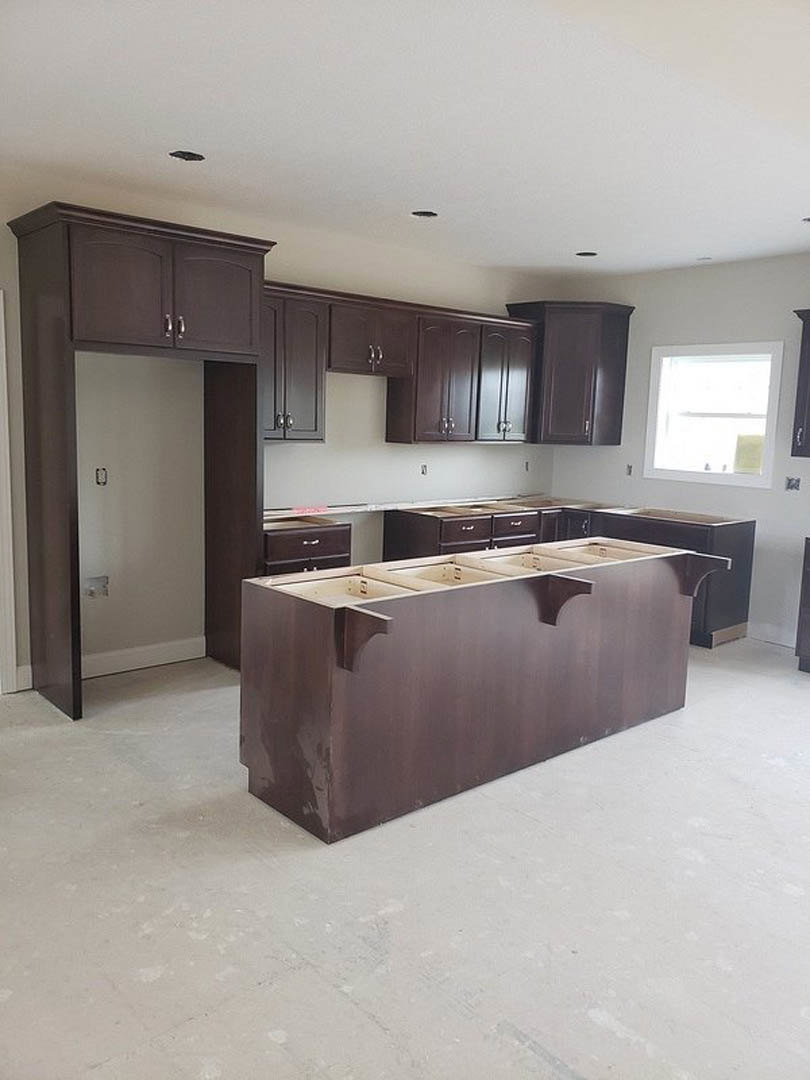 Dark wood kitchen cabinets with brown countertop, four drawers, white framed rectangular window, and sink; close-up of cabinetry and drawer details.