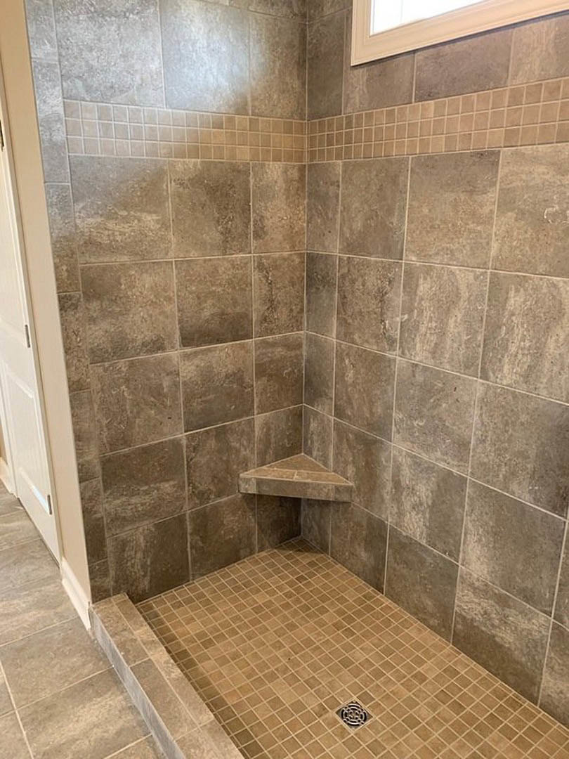 Walk-in shower with marble tile floor, linear drain, and white tiled walls