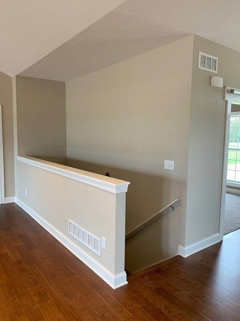 Hardwood staircase with white plaster walls, ceiling vent, and light plywood flooring in a modern residential interior