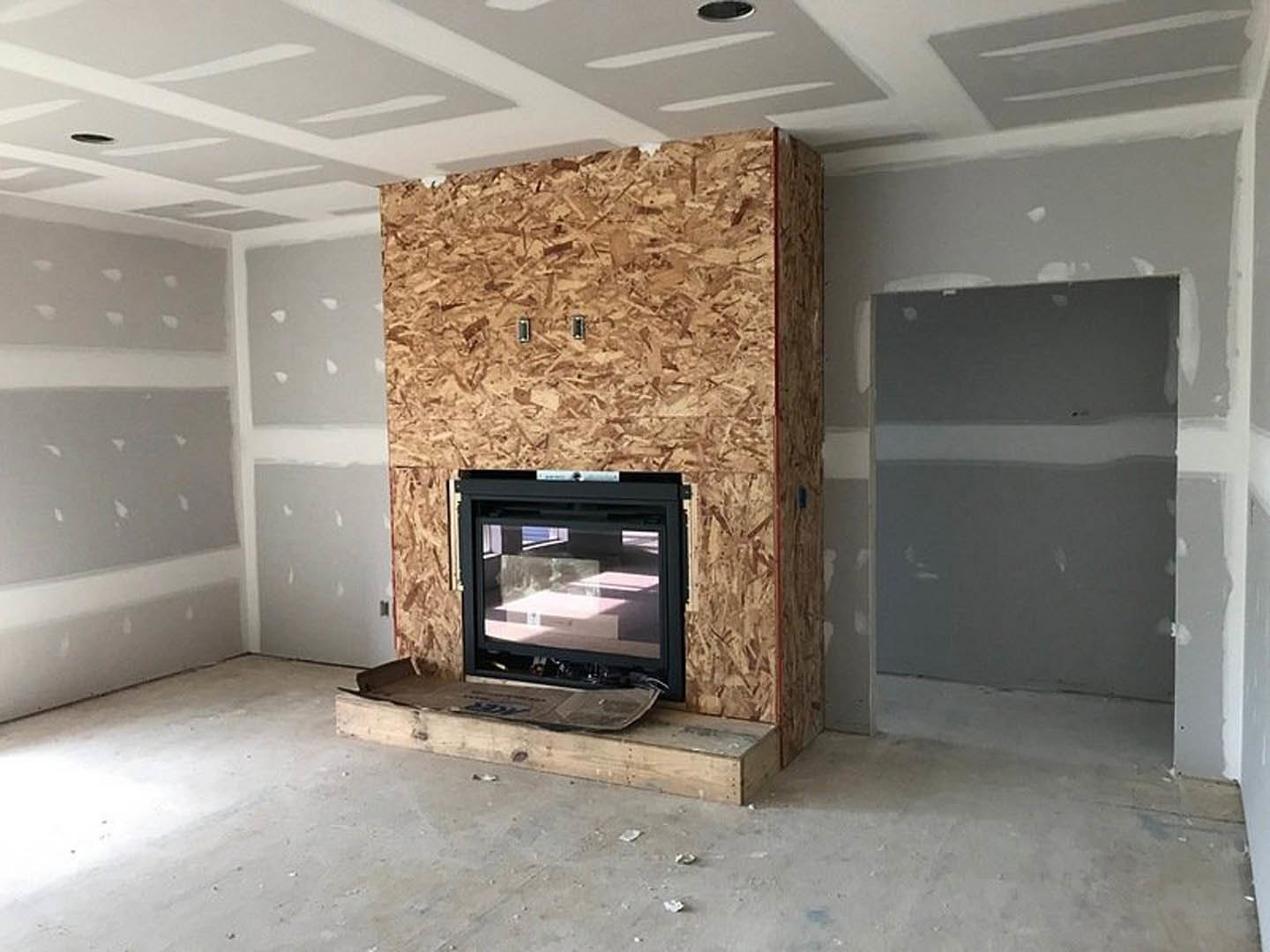 Modern living room with white walls, wood flooring, built-in fireplace, and flat-screen television
