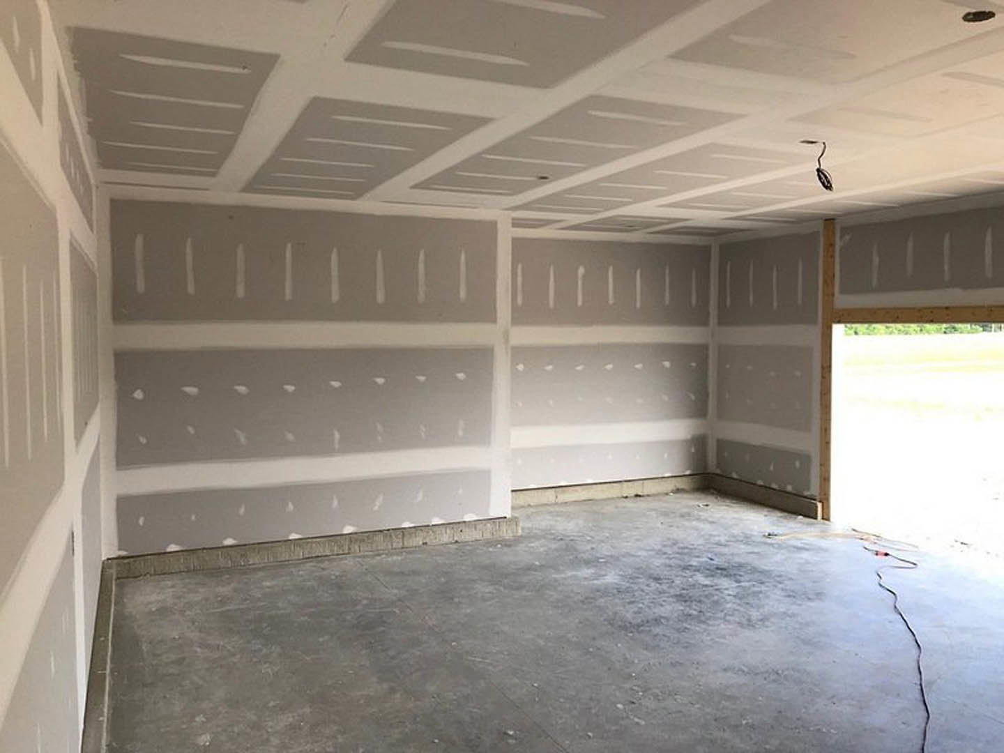 Concrete floor and white plaster walls in an empty room with a white ceiling featuring linear detailing, large window, and a black curved object near the wall.
