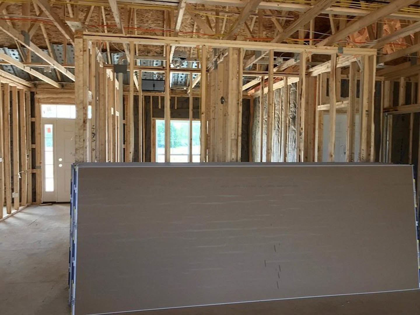 White door with frosted glass window set in a wall, exposed wooden ceiling beams, yellow rope hanging, whiteboard with silver frame, concrete floor, multi-pane window.