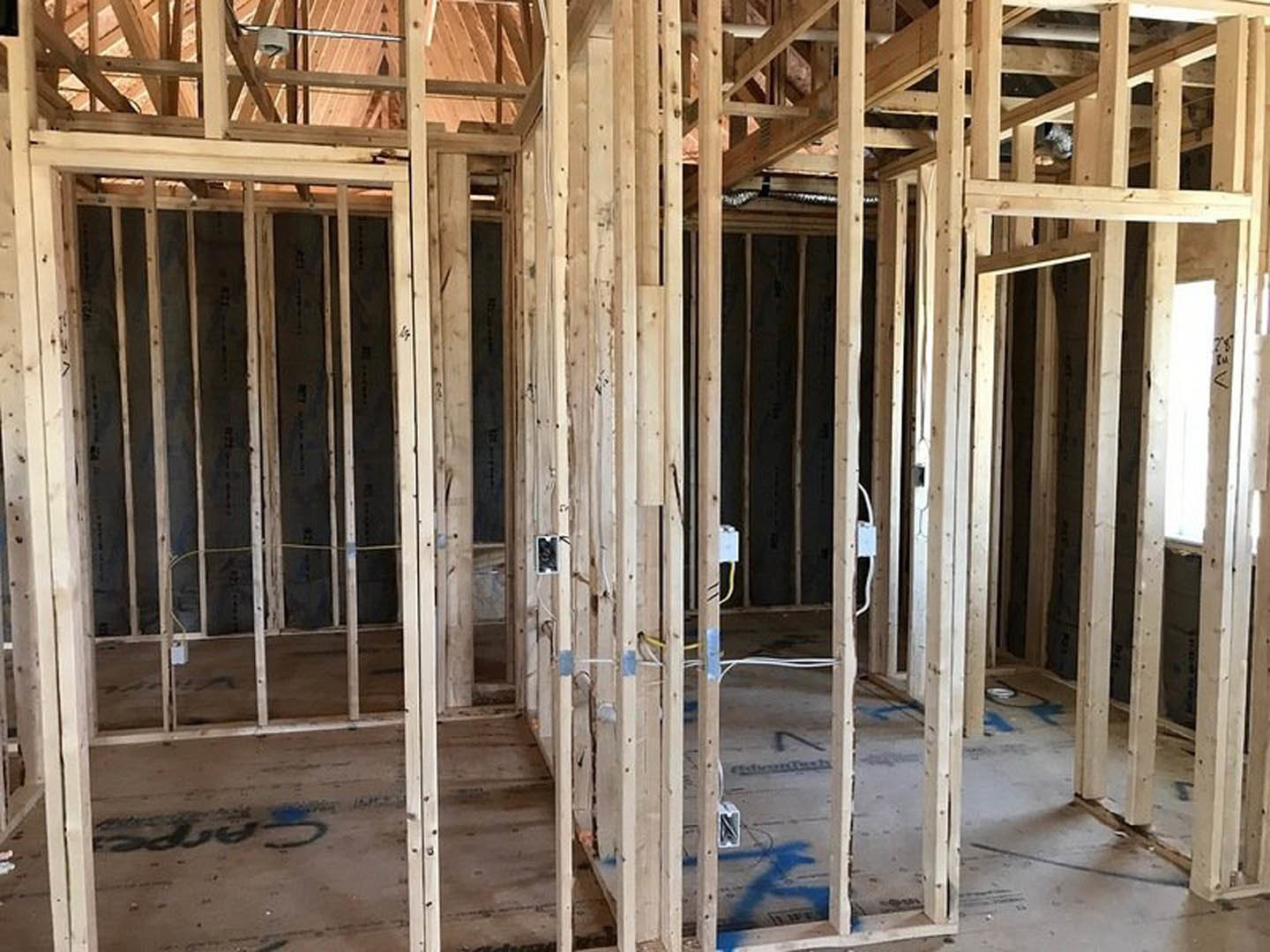 Exposed wooden beams and framing inside a residential construction site with visible insulation and lumber