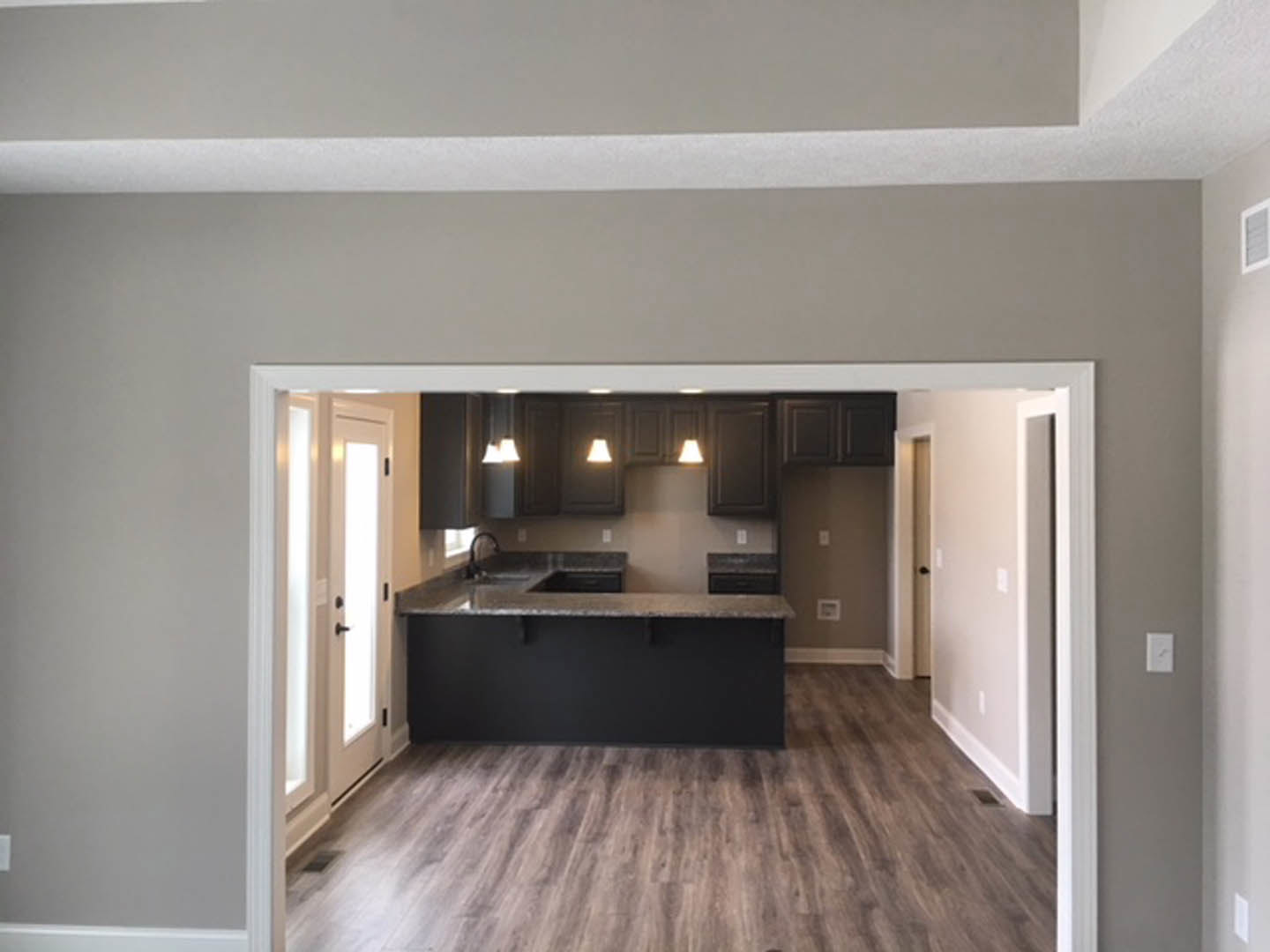 Kitchen and dining area with wood flooring, black accent wall, black countertop, plaster ceiling, and white molding