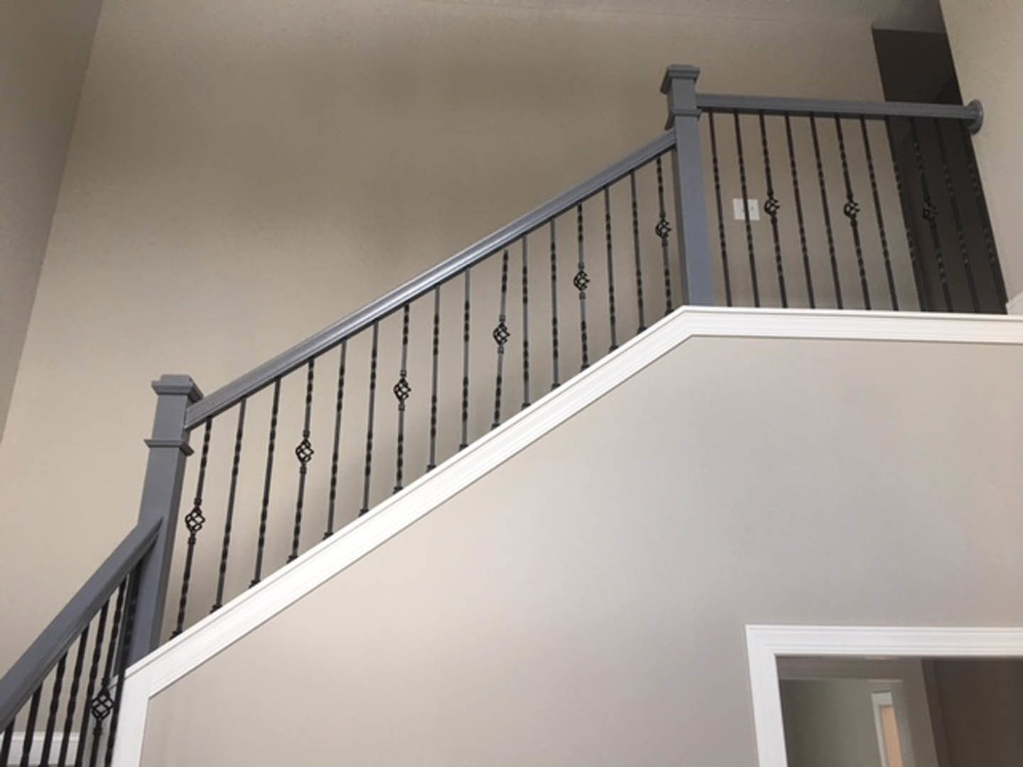 Modern staircase with black metal railing, white walls, and a door frame with glass window in a bright interior