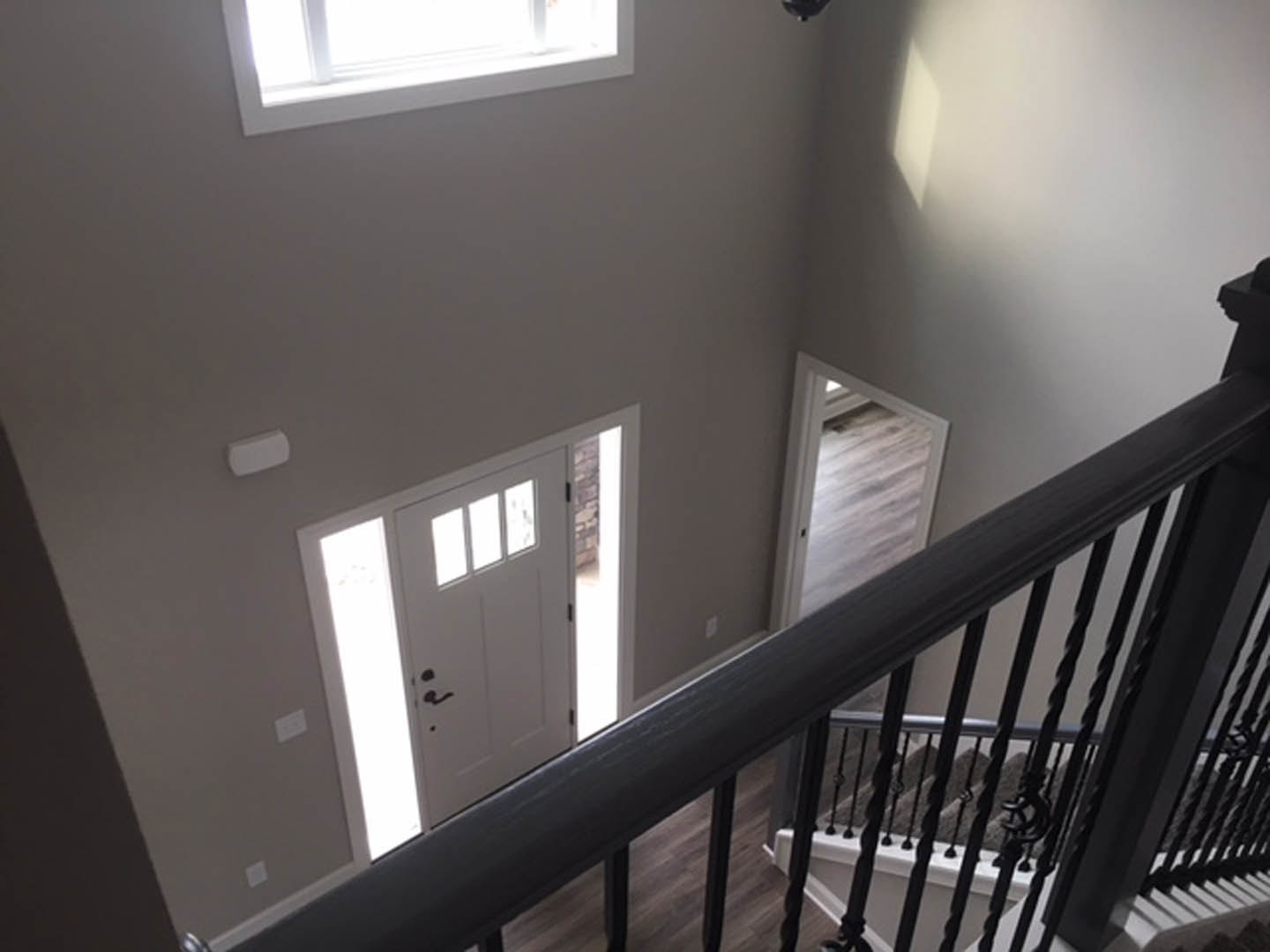 Wood staircase with white balusters and handrail next to a white paneled door with glass windows, plaster walls, and a white light switch.