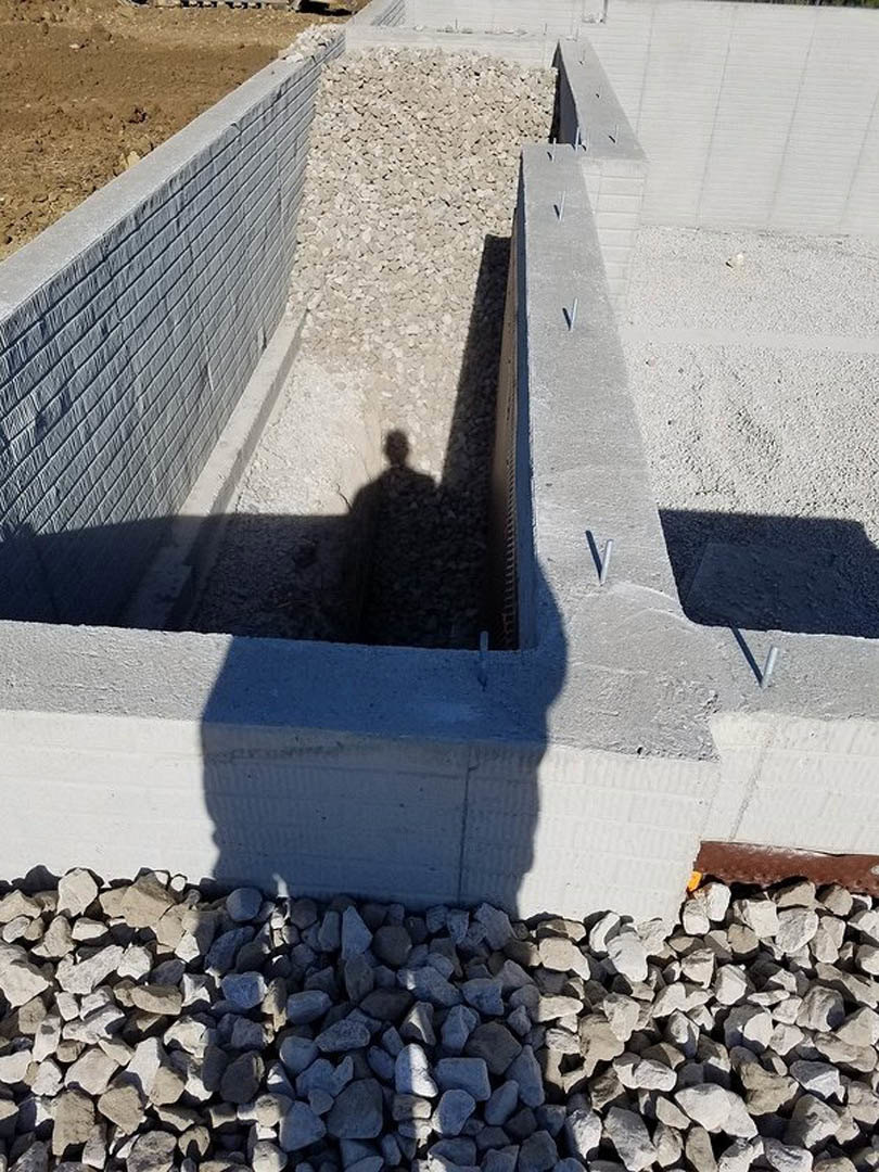 Shadow of a person cast on a textured concrete wall with stone accents at the base