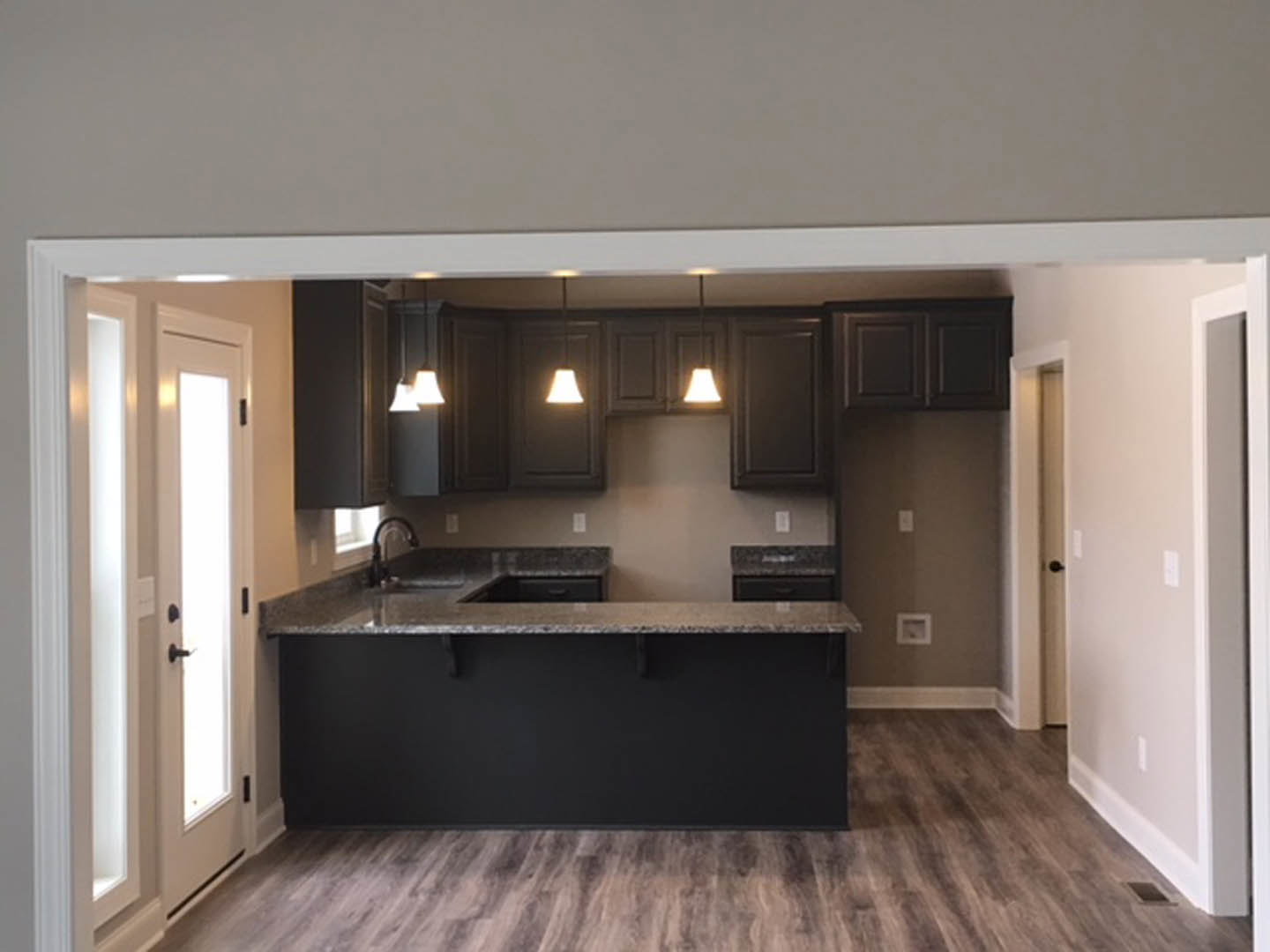 Modern kitchen with tile flooring, white cabinetry, stone countertop with built-in sink, and a square wall frame above the counter.