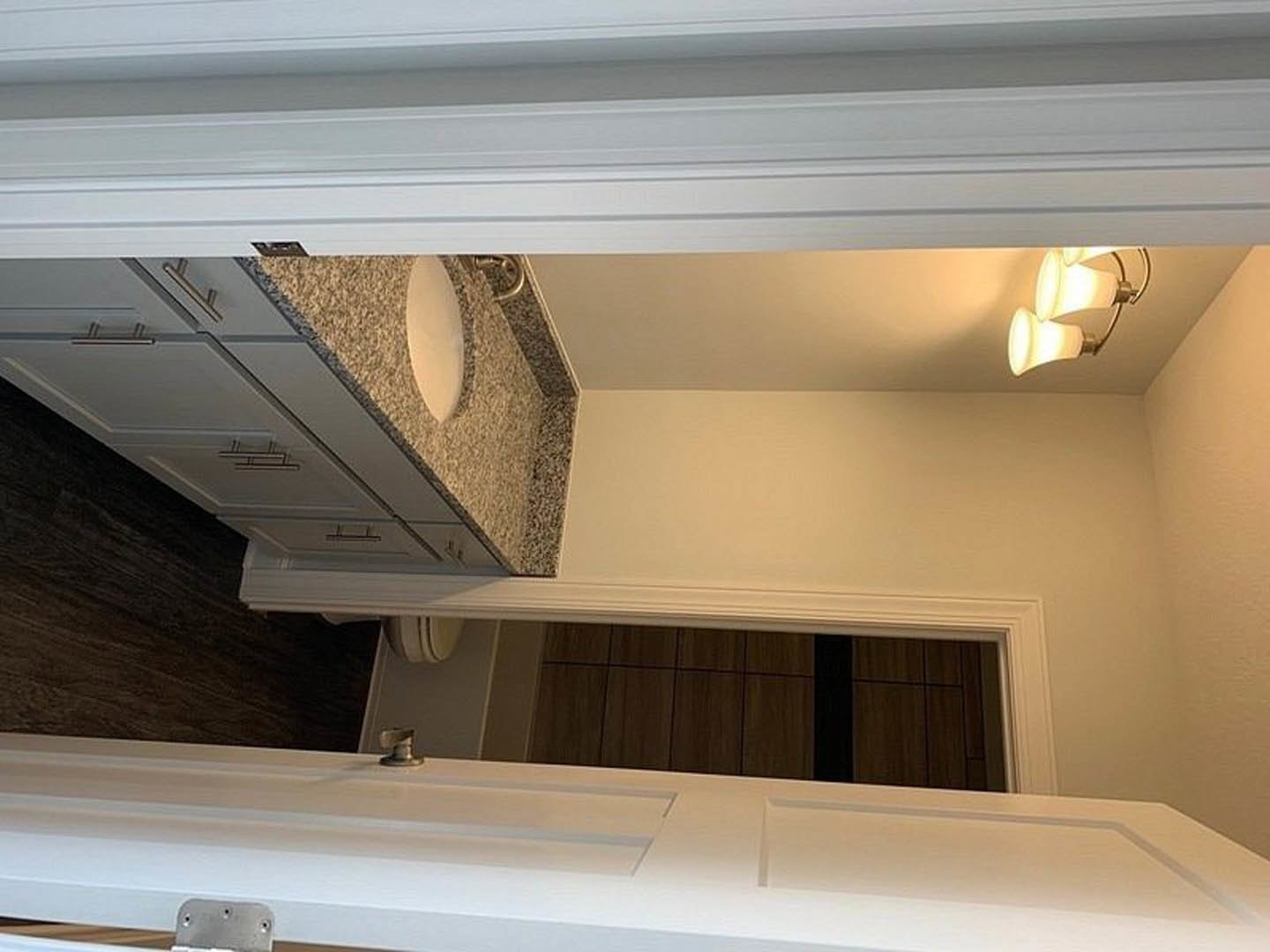 Modern bathroom with white porcelain sink, wall-mounted toilet, plaster walls, recessed ceiling light, and window with white trim