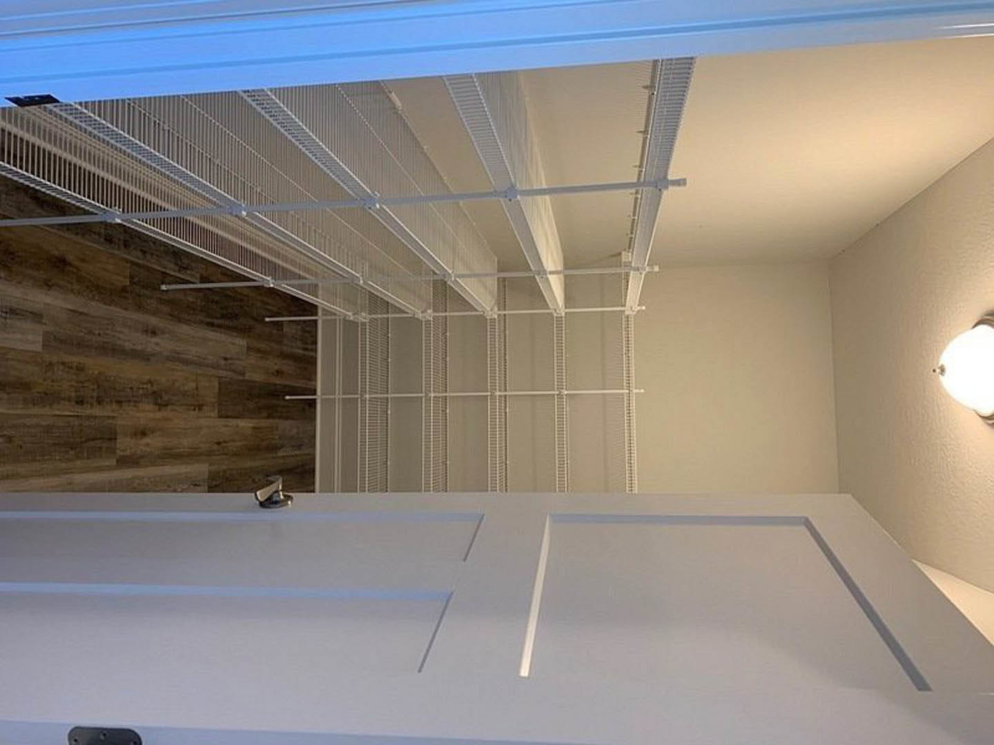 Walk-in closet with white built-in shelves, wood flooring, and blue ceiling with recessed lighting