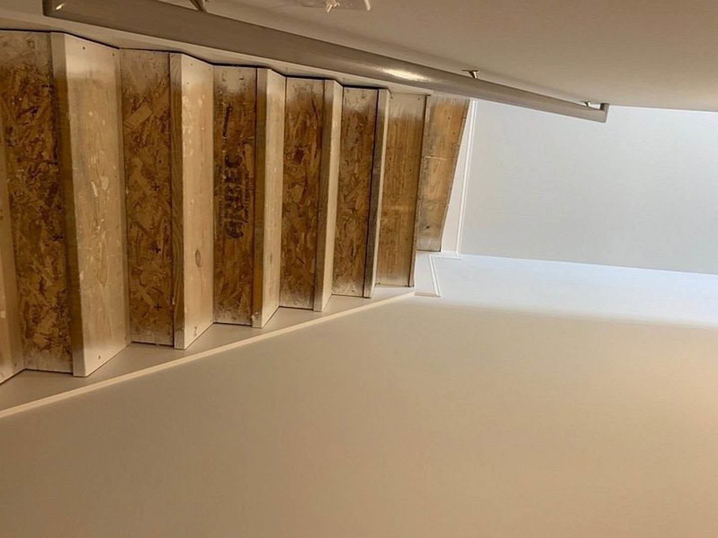 Staircase with wide wood planks, white walls, exposed wooden beam, and metal frame accents