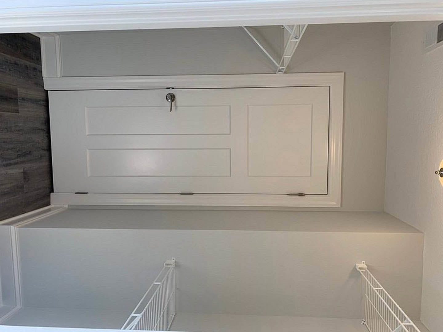 White paneled door with silver keyhole, adjacent white cabinet with metal hook, black countertop, and white railing mounted on plaster wall in bathroom with tub and shower
