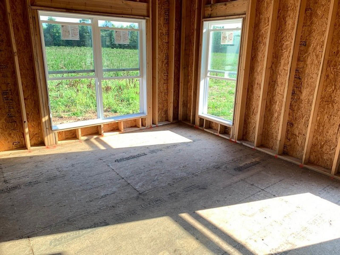 Spacious room featuring large windows, polished concrete floor, wood trim, and views of grassy field outside