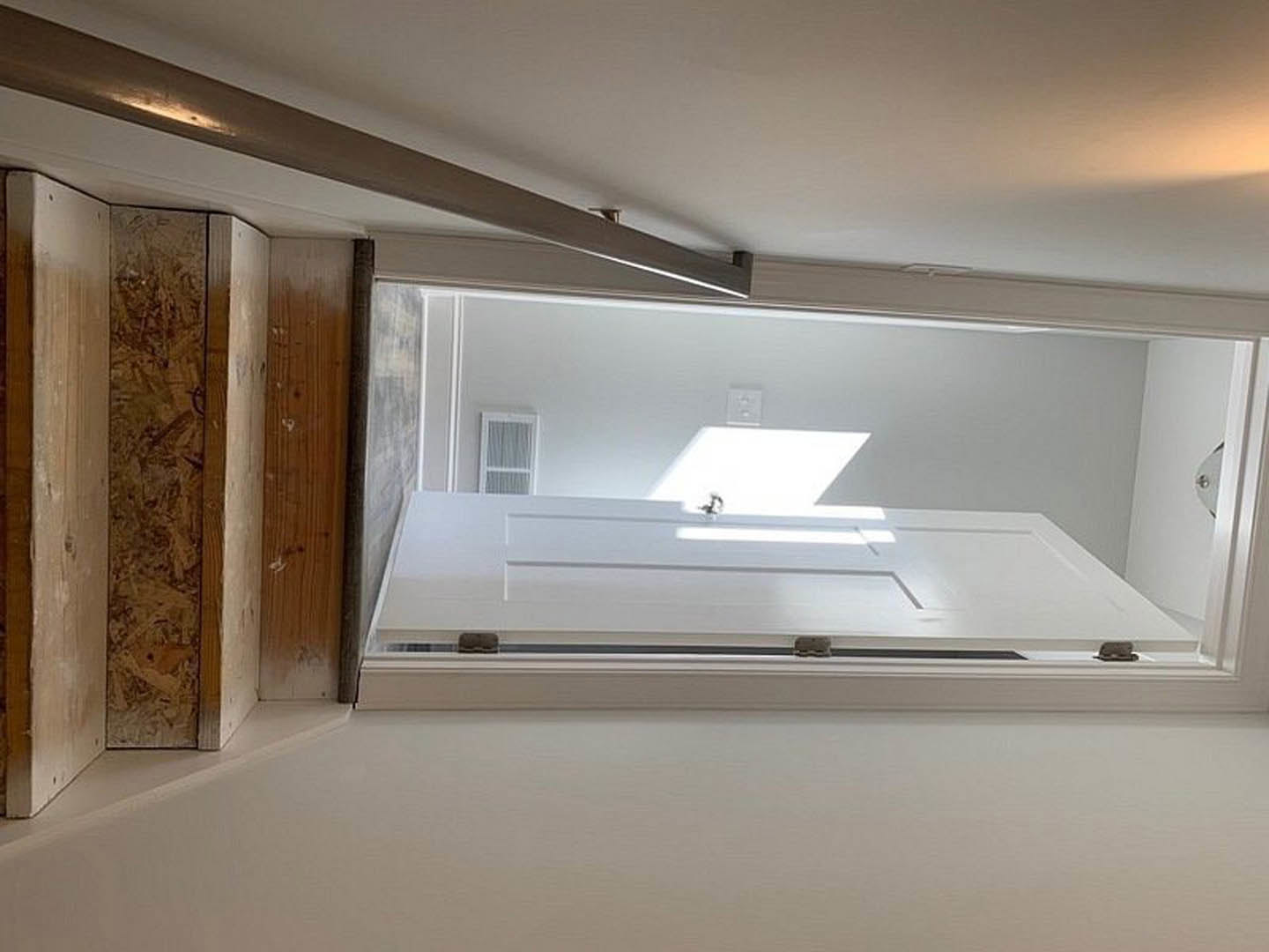 White door with central wooden box, white outlet with knobs, light streaming through doorway, close-up of wood panel, white door with white panel, blurred figure in white-walled