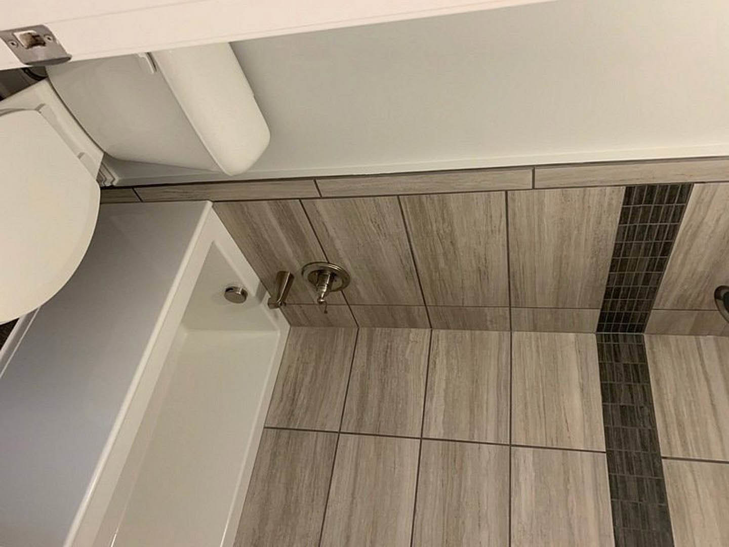 Modern bathroom with freestanding white tub, wall-mounted toilet, large tile wall, light plaster finishes, and minimalist fixtures
