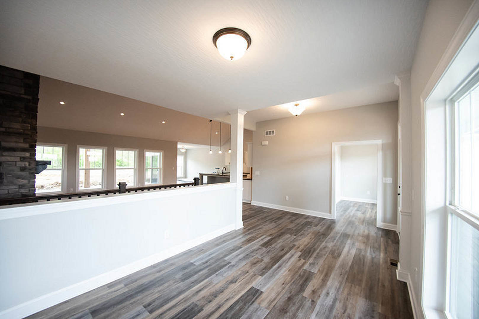 Living room with hardwood flooring, white walls, ceiling light fixture, and exposed brick accent wall