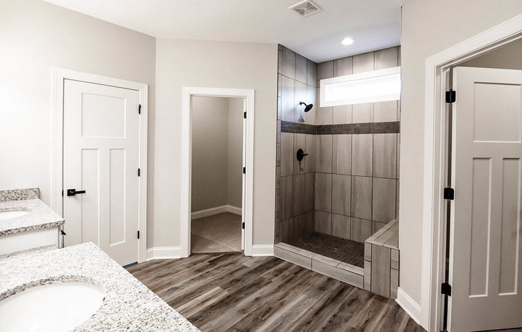 White bathroom with glass-enclosed shower, modern vanity with rectangular sink, chrome faucet, and light gray tile flooring