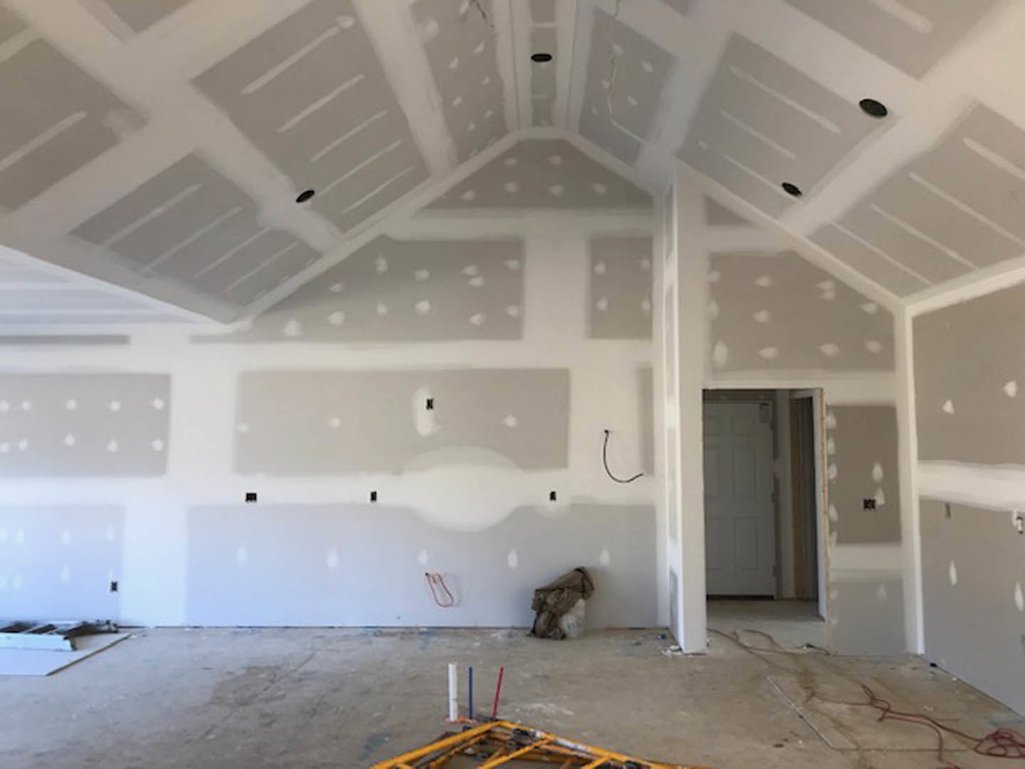 White-walled room with white ceiling, white door, square tile flooring, exposed pipes on the ground