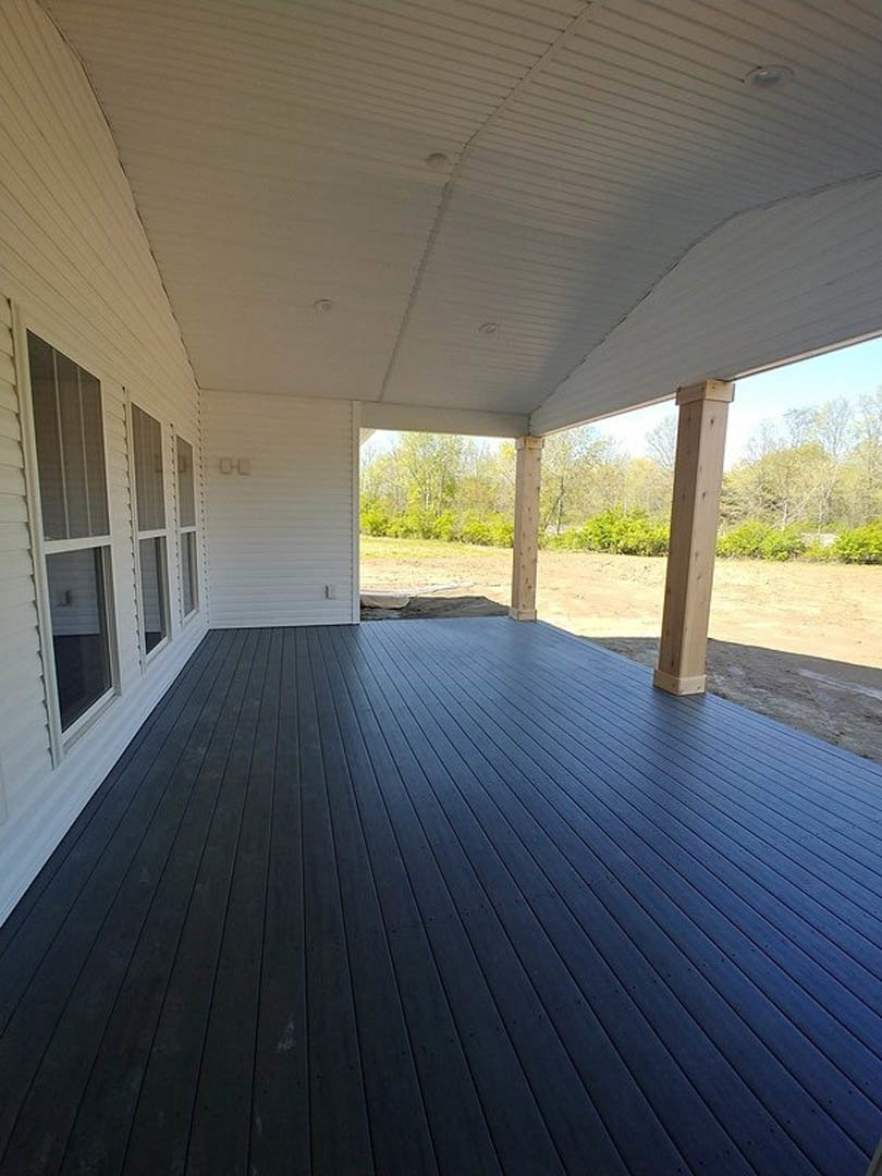 Deck with white wall, blue floor, white door, wooden post with visible nails, white ceiling featuring recessed lights, close-up window adjacent to porch.