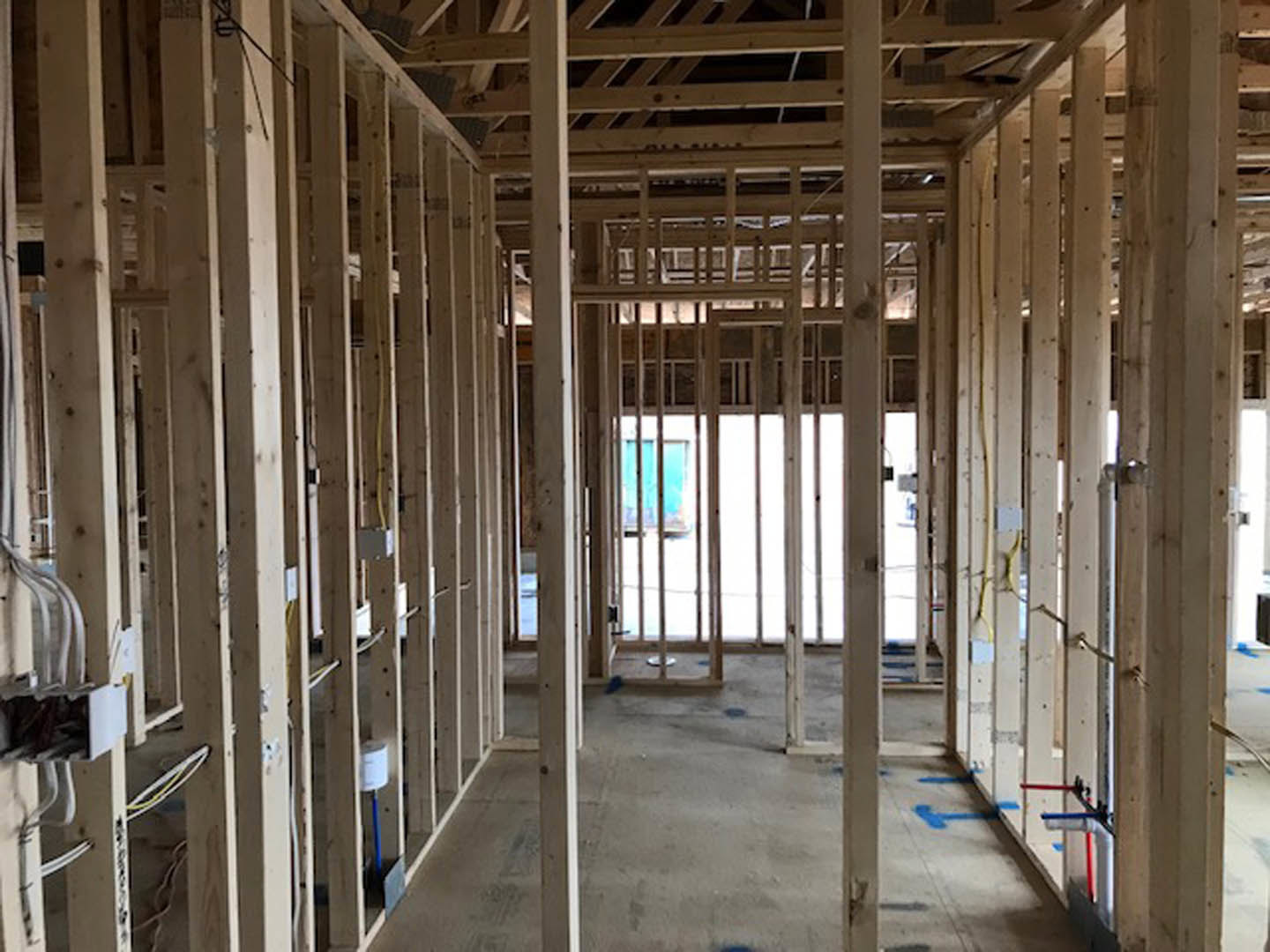 Living room with exposed wood ceiling beams, large window, white walls, and concrete floor.