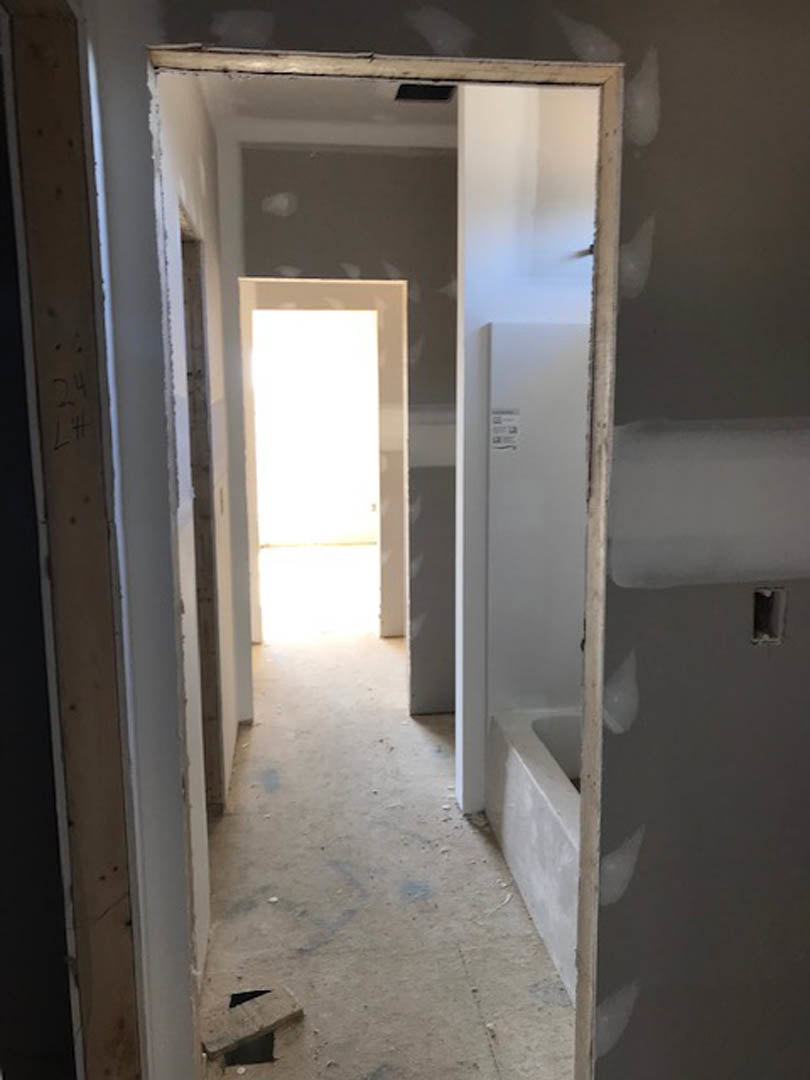Hallway with plaster walls, open door, and freestanding white tub on tiled floor