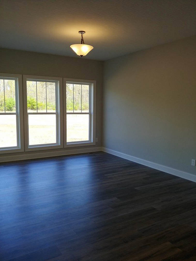 Dark wood flooring, white ceiling with a modern light fixture, row of large windows offering outdoor views, neutral wall finishes.