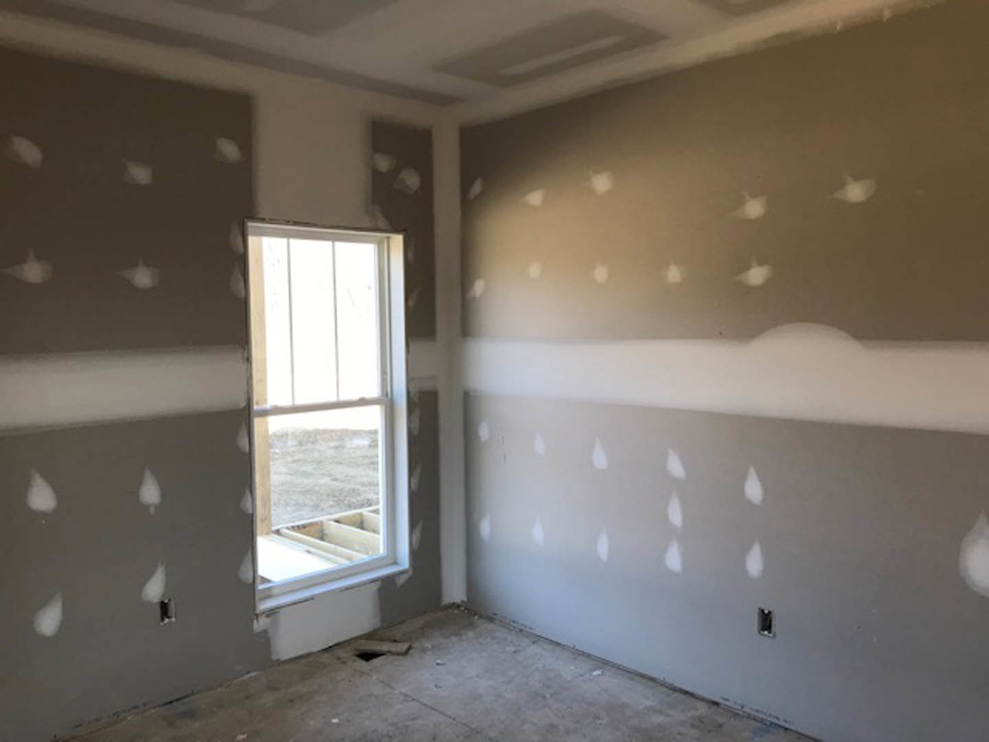 White-painted walls, concrete floor with central hole, large window providing daylight, smooth plaster ceiling