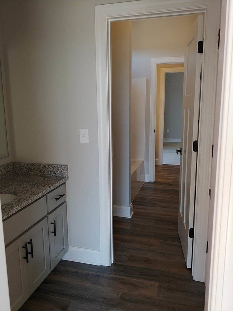 Bathroom featuring a marble countertop with undermount sink, white cabinetry, tile flooring, and partial view of a wooden door.